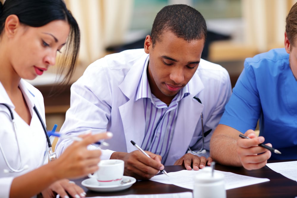 Young african-american doctor making notes at the medical meeting-1